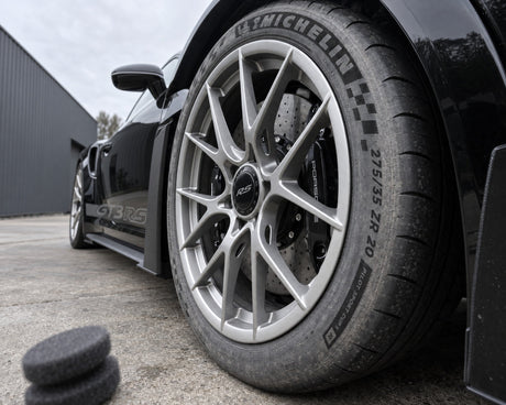 Detailing1 Koch-Chemie Handpolierschwamm Puck vor stumpfer Reifenflanke am schwarzen Porsche