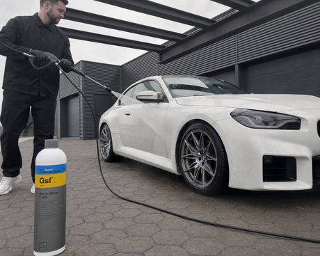 Daniel spült mit dem Hochdruckreiniger die Flanke eines weißen BMW M2 ab, die Koch-Chemie Gentle Snow Foam Flasche steht auf dem Pflaster — gezeigt im Artikel „Auto mit Hochdruckreiniger waschen: Düse, Abstand und Druck