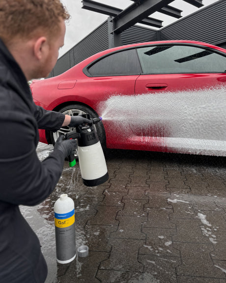 Jasper trägt mit dem iK Sprayers iK Foam Pro 2 dichten Schaum auf die Flanke eines roten BMW M2 auf